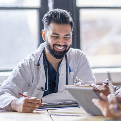 A man wearing a labcoat sits at a conference table