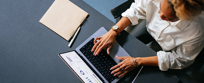 a top view of a lady in professional clothing working on laptop