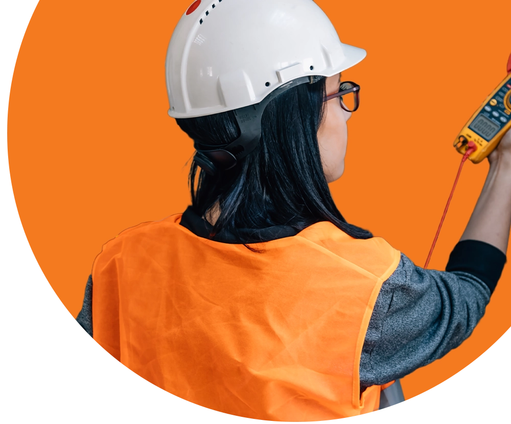 A woman wearing a hardhat checks a measurement device