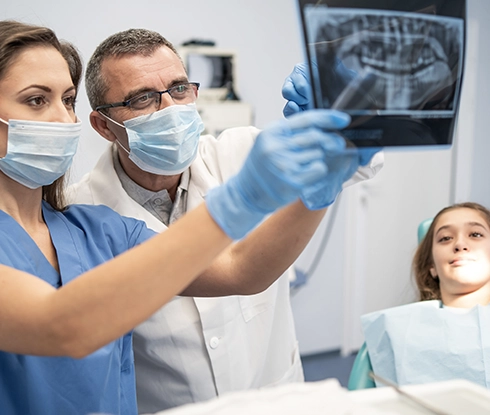 A dental assistant inspects the mouth of a patient