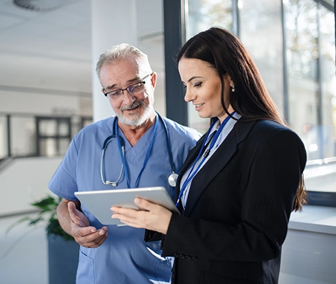 A medical professional wearing a lab coat looking at a tablet