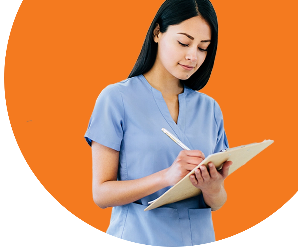 A woman wearing scrubs writes notes on a clipboard.