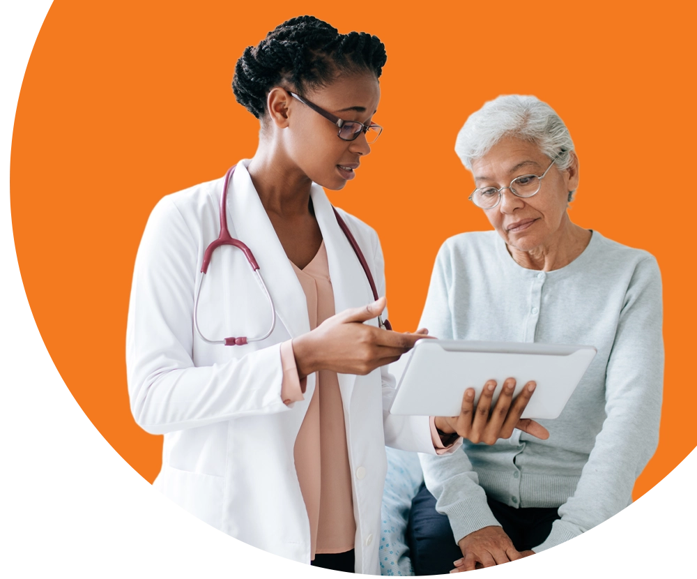 A medical professional wearing a lab coat shows a patient a tablet