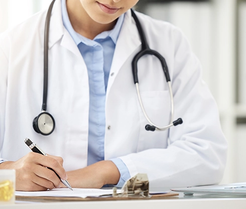 A doctor wearing a labcoat looks at a tablet